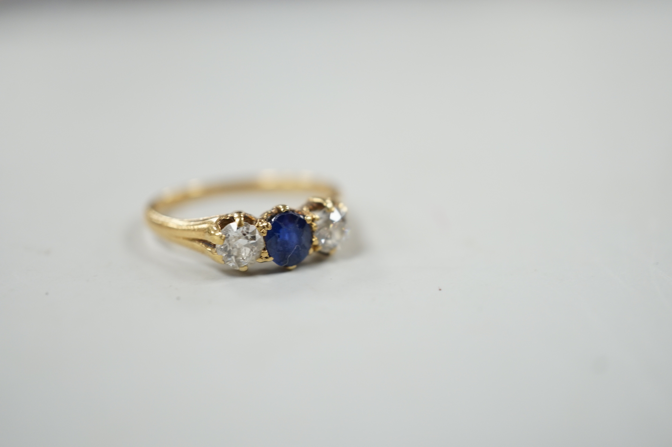A yellow metal, single stone sapphire and two stone diamond set ring, size L, gross weight 2.3 grams.